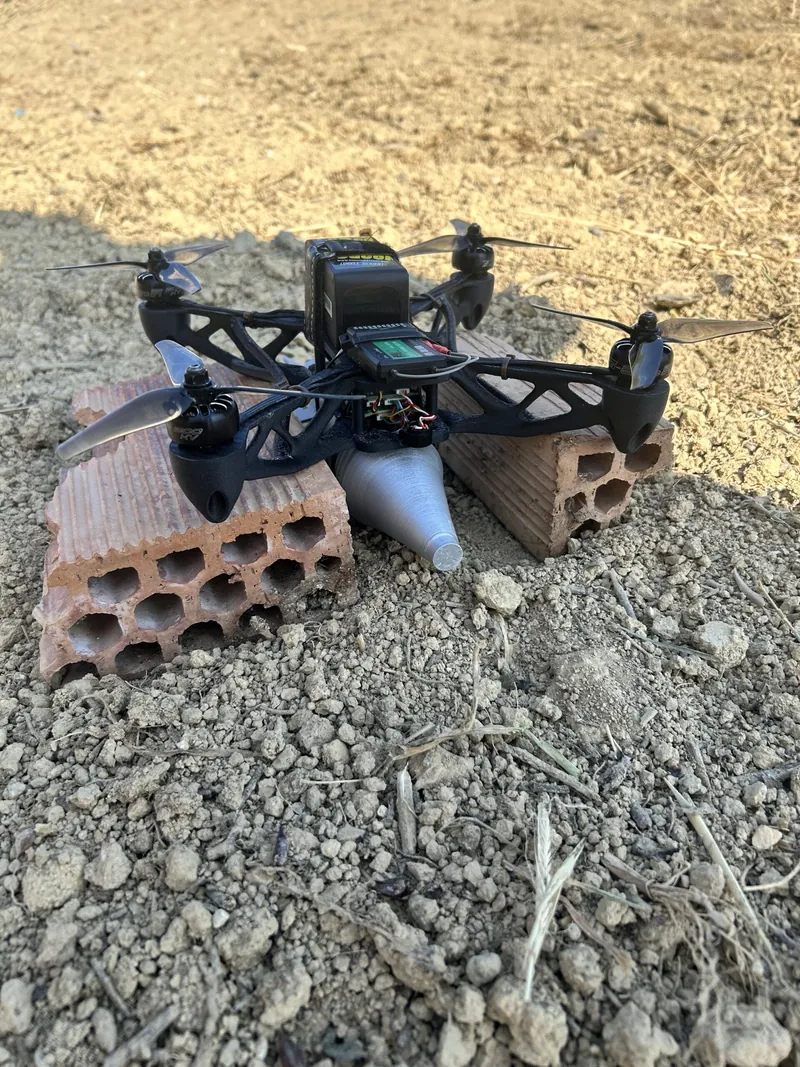 A quadcopter drone resting on bricks in a field